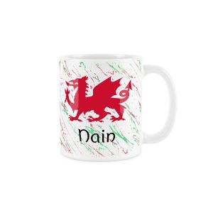White ceramic mug with a red welsh dragon,splattered red and green background and nain (grandma) text